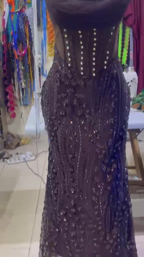Dark embellished gown with a draped neckline.